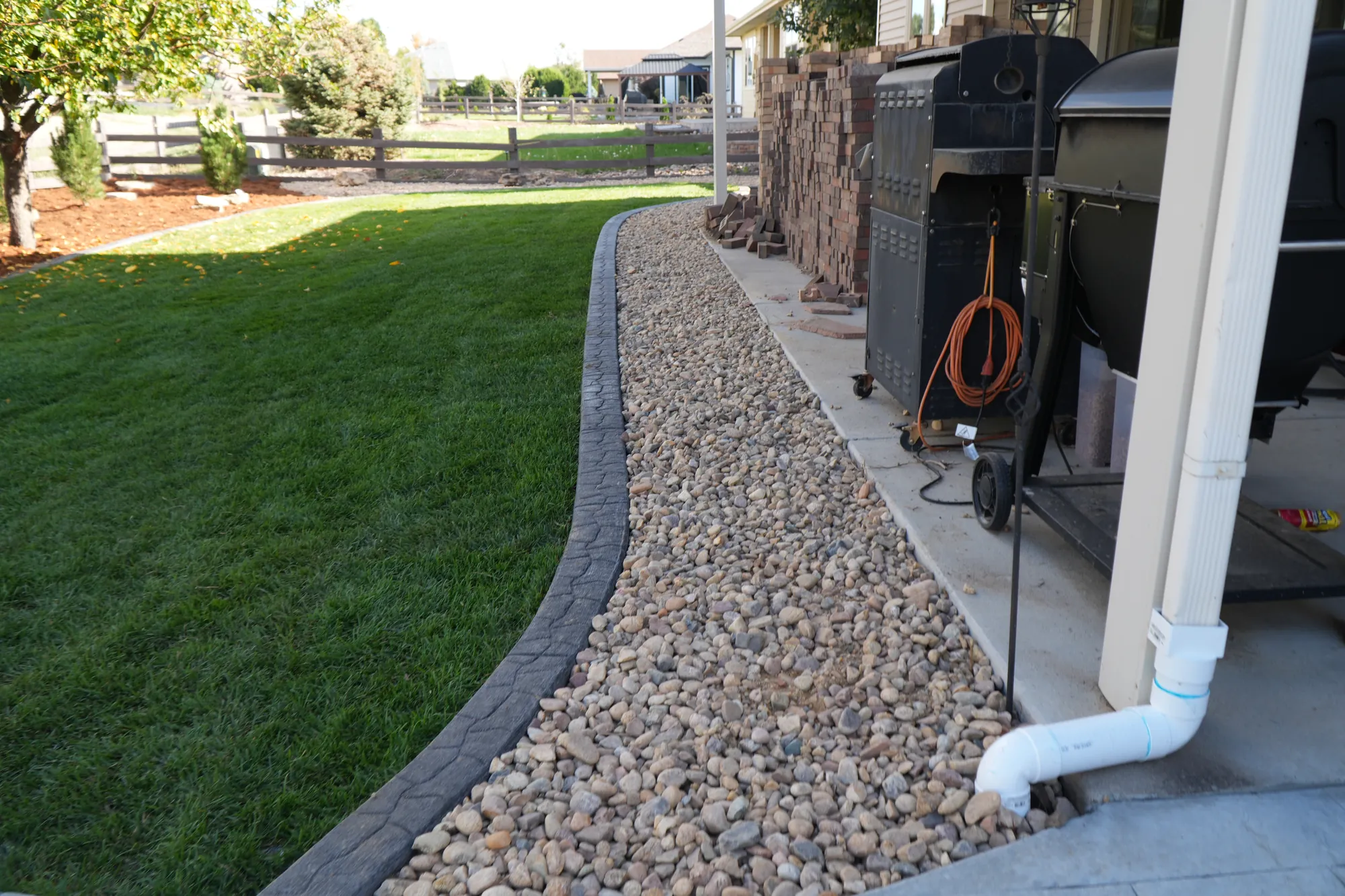 Rock Landscaping: river rock strip with curbing along the side of the house